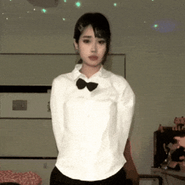a woman in a white shirt and black bow tie is standing in a room