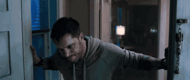 a man is leaning against a door with his arms outstretched .