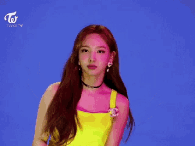 a woman in a yellow tank top giving a peace sign