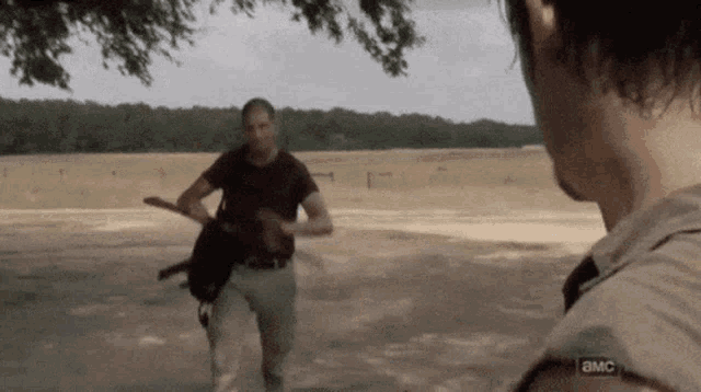 two men are standing in a field and one of them is wearing a shirt that says ' a.m.c. '