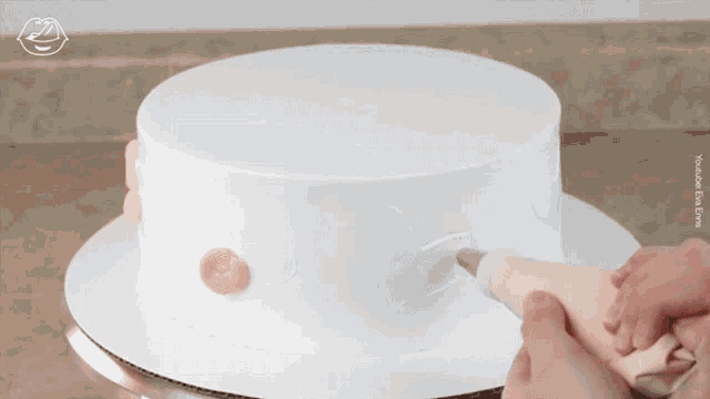 a person frosting a cake with a piping bag and a youtube link
