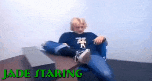 a blurry picture of a person sitting at a table with the words `` jade staring '' on the bottom .