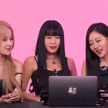 three women are sitting in front of a laptop computer on a table .
