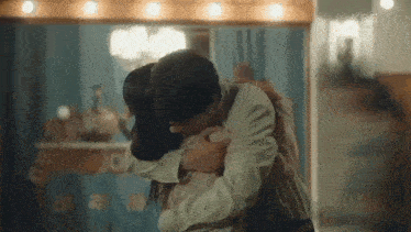 a man and a woman are hugging each other in front of a mirror .