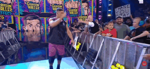 a grayson waller effect sign is on a fence behind a wrestler