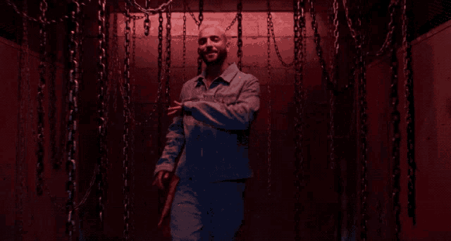 a man in a prison uniform is standing in a room with chains hanging from the ceiling