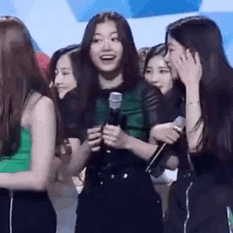a group of girls are standing next to each other holding microphones and smiling .