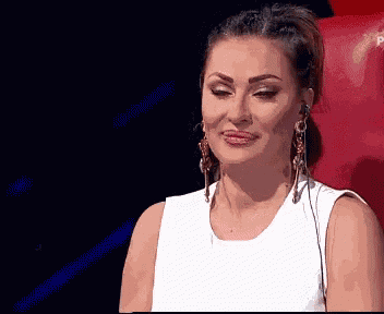 a woman in a white dress and gold earrings is sitting in a red chair