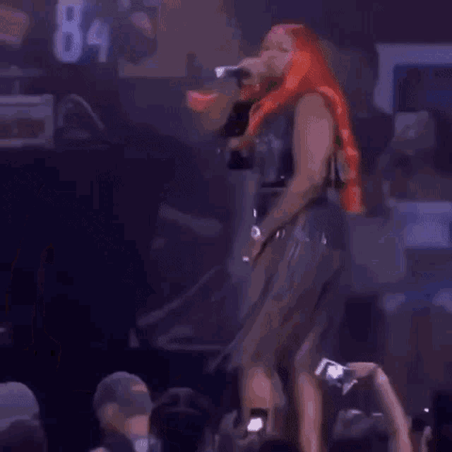 a woman with red hair is singing into a microphone on stage .