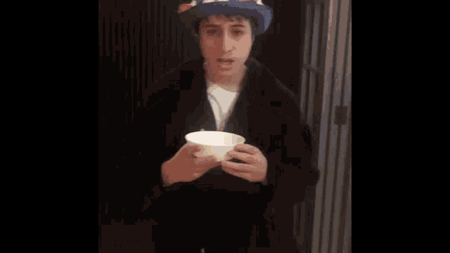 a man wearing a top hat with rabbits on it is eating a bowl of food .