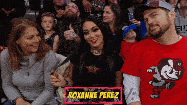 roxanne perez sits in a crowd of people wearing a red shirt with mickey mouse on it