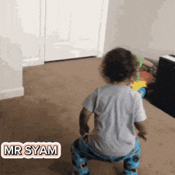 a baby is standing on his knees in a room with a sticker that says mr syam .