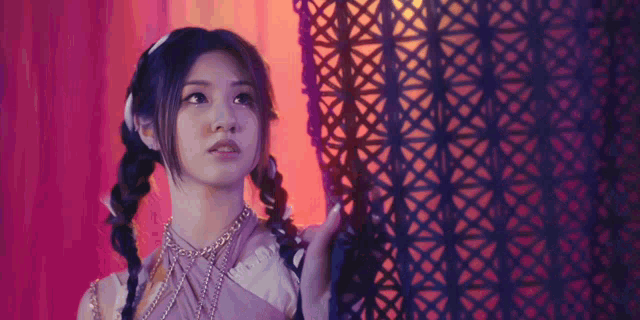 a woman with pigtails and a necklace looks up at something