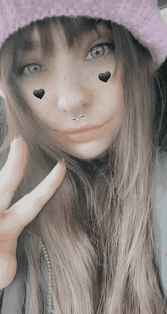 a woman wearing a purple hat has two hearts on her face