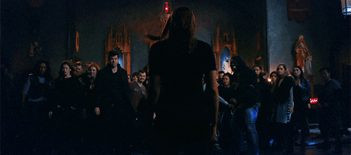 a woman stands in front of a group of people in a dark room with blue lights