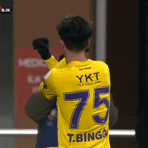 a soccer player wearing a yellow jersey with the number 75