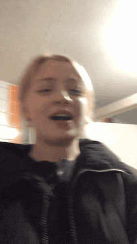 a woman in a black jacket is smiling and laughing
