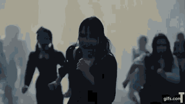 a group of people are running through a foggy room .