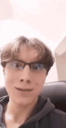 a young man wearing glasses is smiling for the camera .