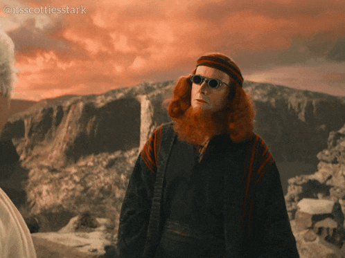 a man with red hair and sunglasses is standing in front of a mountain with the caption it 'sscottiesstark