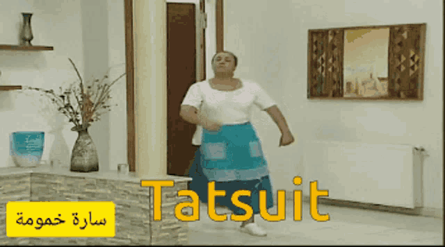 a woman in a blue apron is dancing in a room that says tatsuit on the floor