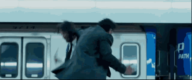 a man in a suit is fighting another man on a train .