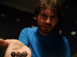 a man with a beard wearing a blue shirt is covering his mouth with his hand