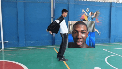a man is standing on a basketball court with a picture of a man in the background