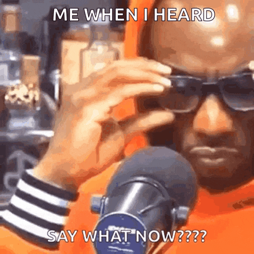 a man wearing sunglasses is sitting in front of a microphone and saying me when i heard say what now ?