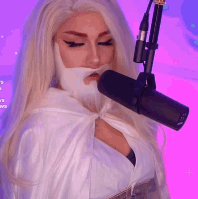a woman wearing a white cape is standing in front of a microphone with a pink background