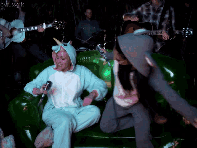 a woman in a unicorn costume is singing into a microphone in front of a band