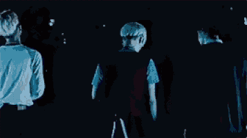 two men are hugging each other in a dark room in a dark room .