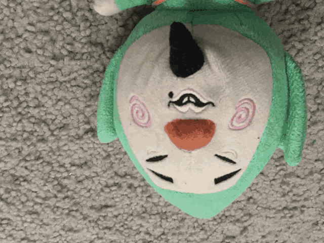 a green and white stuffed animal is laying on its back