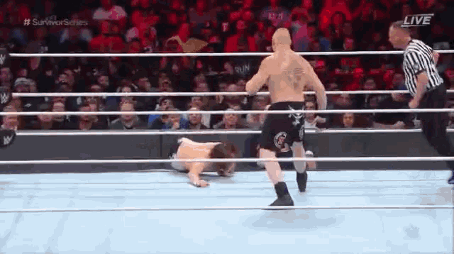two men are wrestling in a wrestling ring with a referee watching .