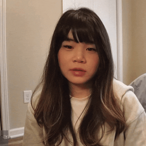 a woman with long hair and bangs wearing a white sweater