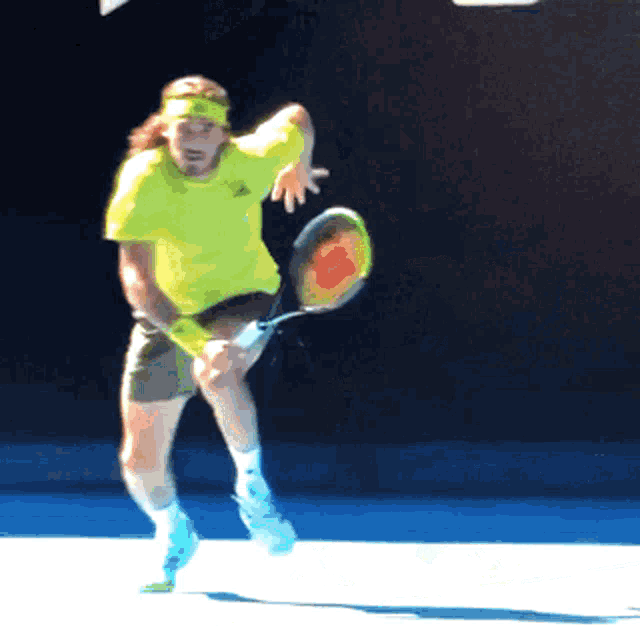 a tennis player in a yellow shirt is swinging a wilson racquet