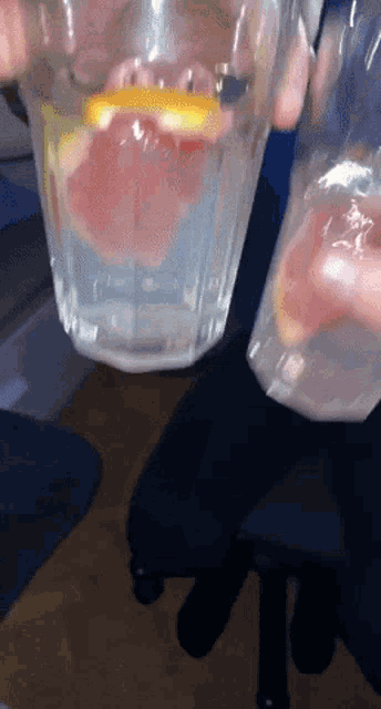 someone is holding a glass of water with a slice of lemon in it