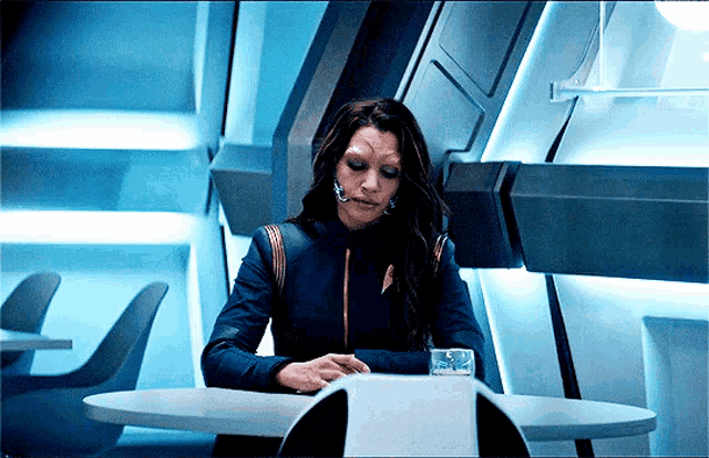 a woman is sitting at a table with a glass of water