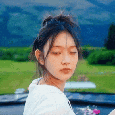 a close up of a woman with her eyes closed in front of a field .
