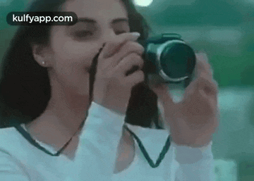 a woman is taking a picture with a camera and covering her face .