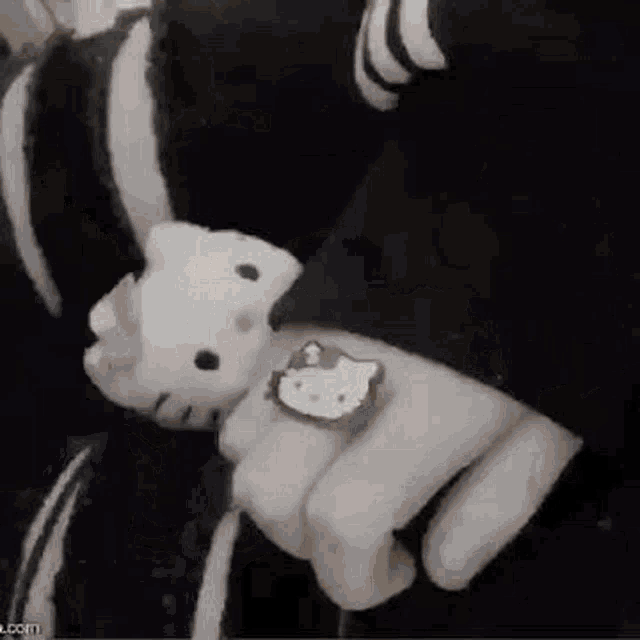 a person wearing a hello kitty ring is holding a stuffed hello kitty .