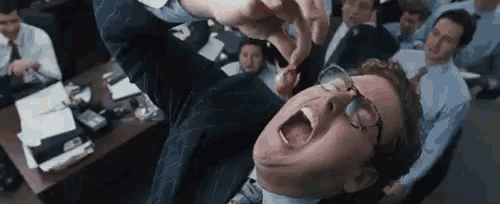 a man in a suit is laying on his back with his mouth open .
