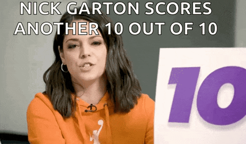 a woman in an orange hoodie holds up a sign that says nick garton scores another 10 out of 10
