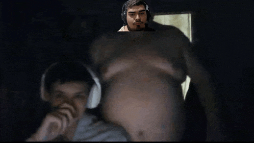 a man wearing headphones is looking at a very large belly of a man .