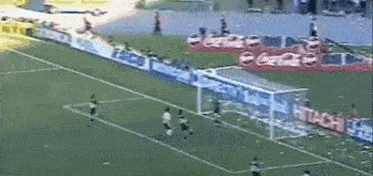 a soccer game is being played on a field with coca cola advertisements on the sidelines .
