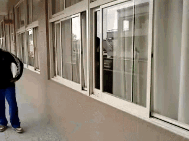 a person is standing in a hallway looking out of a window .