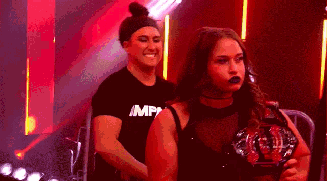a woman in a black top is holding a trophy in front of a large screen with a woman 's face on it .