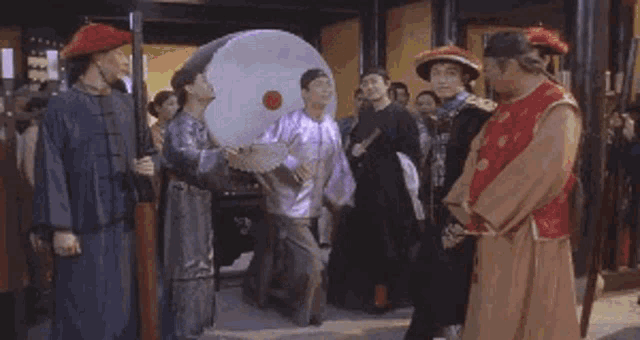 a group of people in traditional costume are standing around a man in a purple shirt .