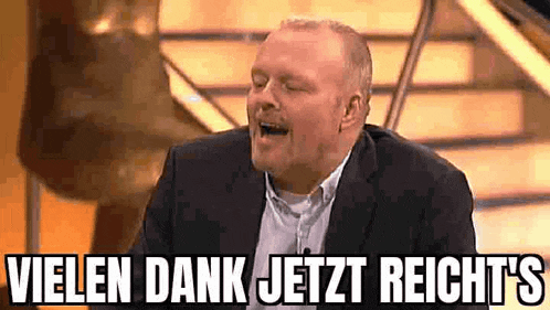 a man in a suit is laughing with the words vielen dank jetzt reicht 's below him .