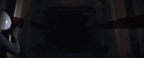 darth vader is holding a red lightsaber in a dark hallway